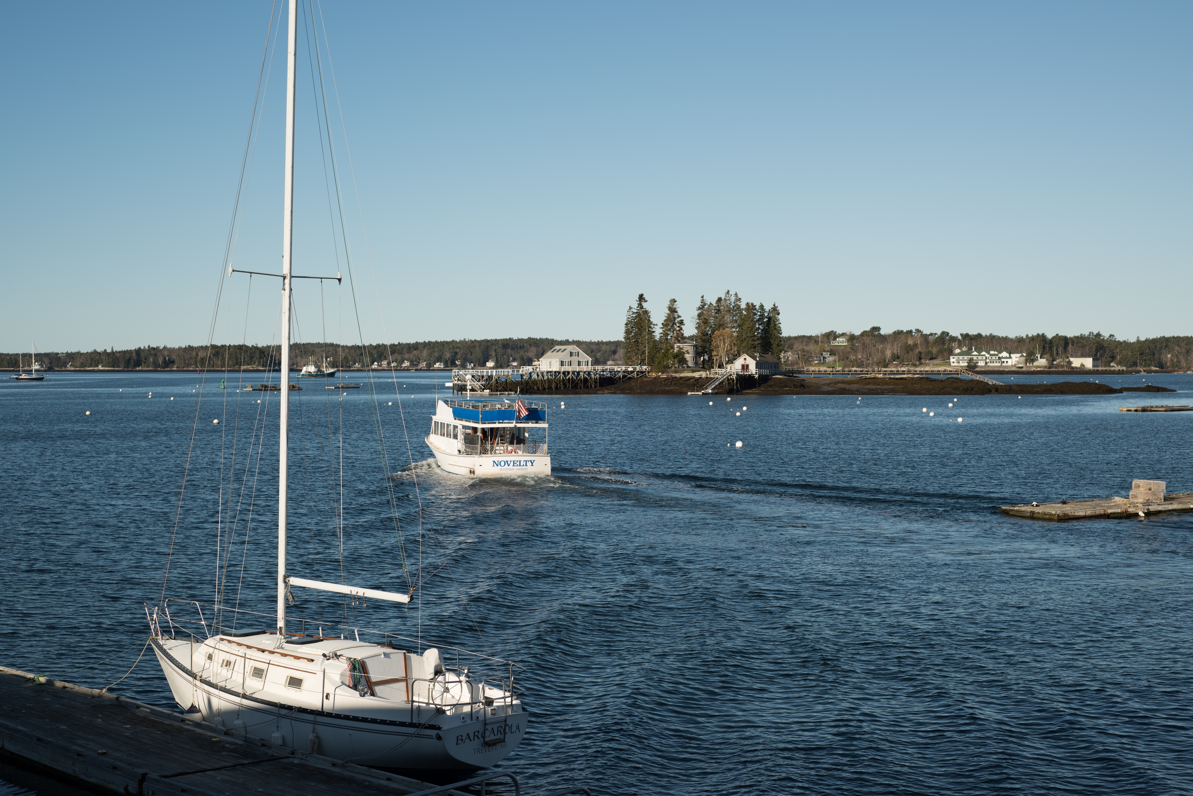 Large harbor and open body of water with a tour boat and a sailboat tied at a dock