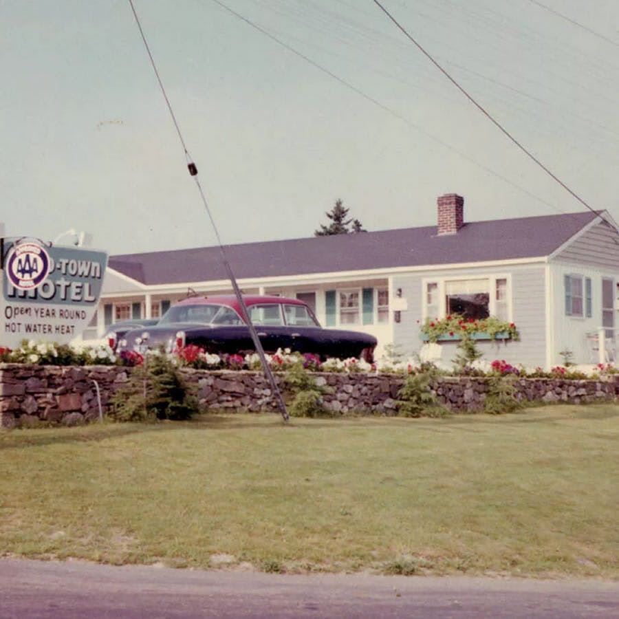 Old time photo of 1950’s car in front of Mid-Town Motel, with wood sign and AAA plaque.