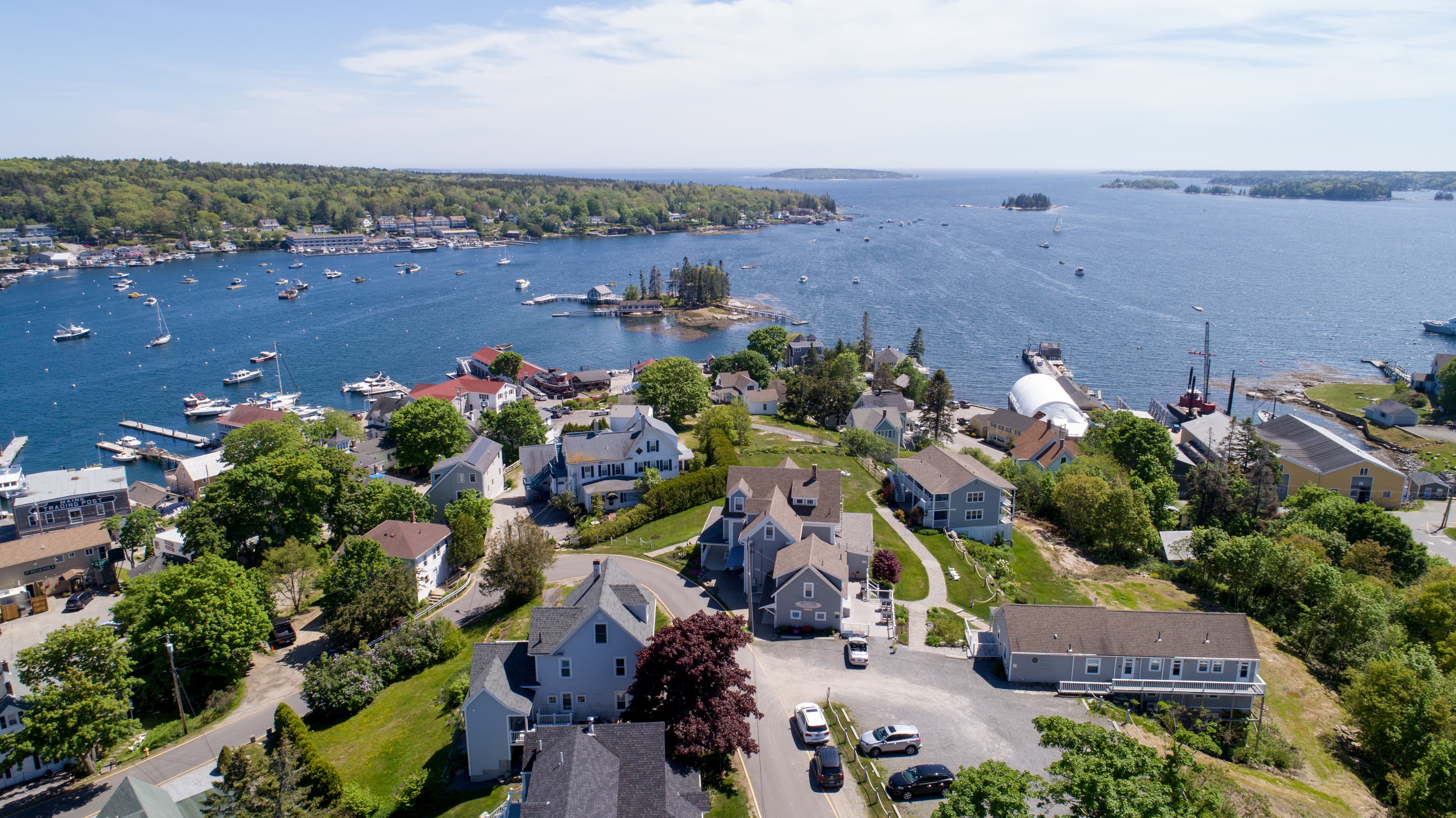 Aerial view of a quaint harbor town at the edge of the water with numerous boats in the water