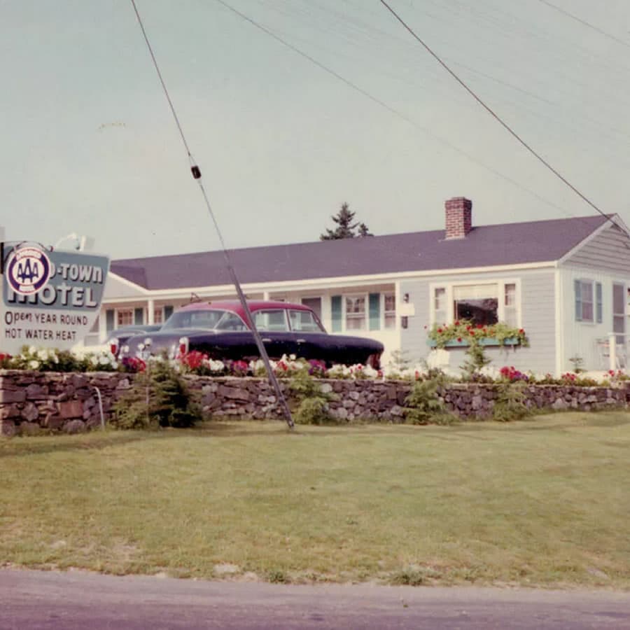 Old time photo of 1950's car in front of Mid-Town Motel, with wood sign and AAA plaque.