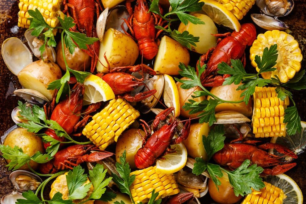 A clambake platter full of corn on the cob, crawfish, clams and potatoes