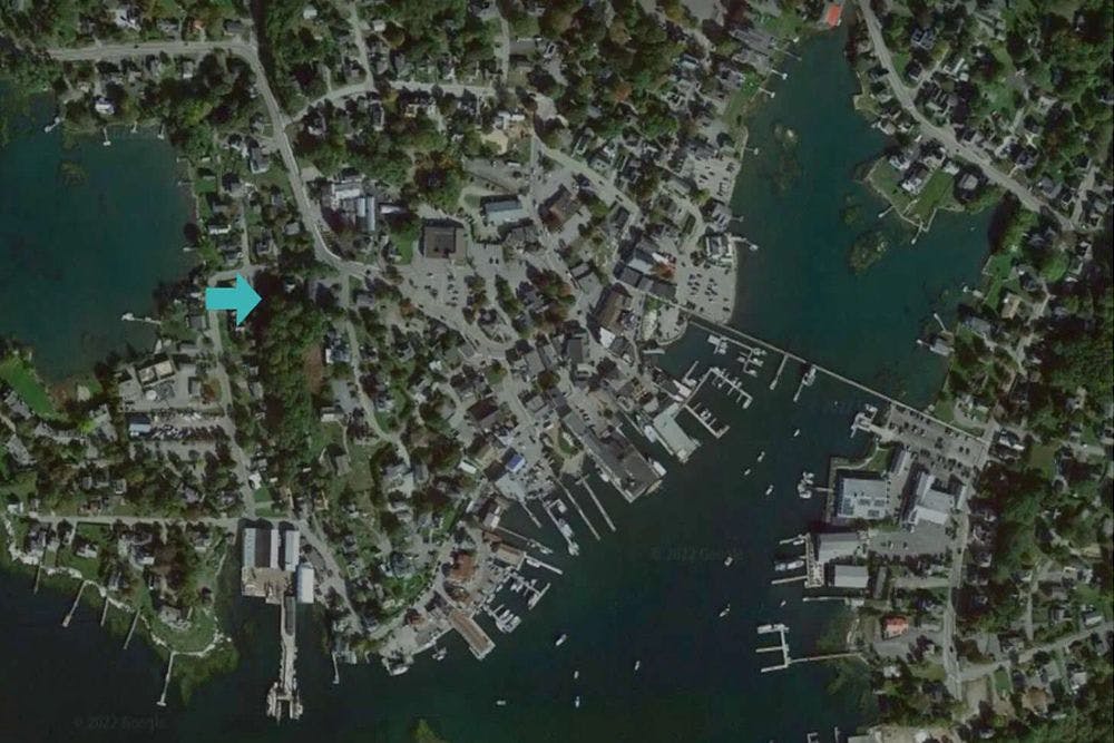 An overhead drone image of a harbor town surrounded by water