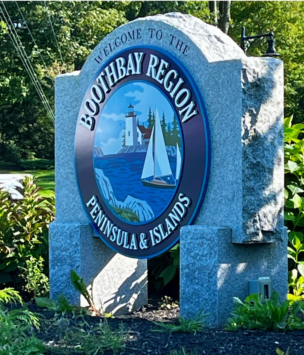 Large stone sign with circular logo welcoming visitors to the region