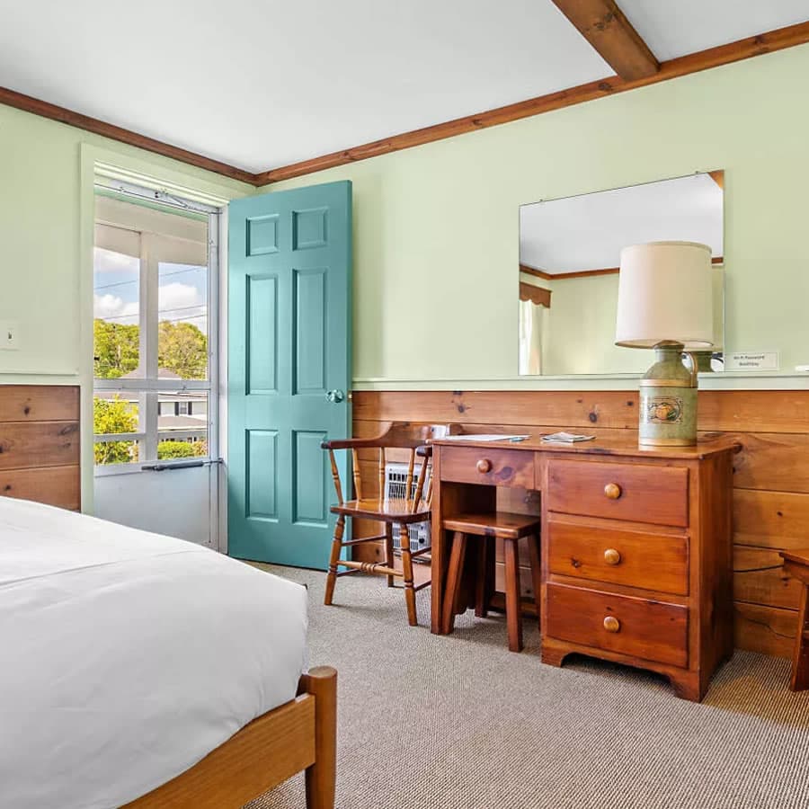 Pine desk and chair, pine chair rail, teal door, lamp and, all mirror and green walls.