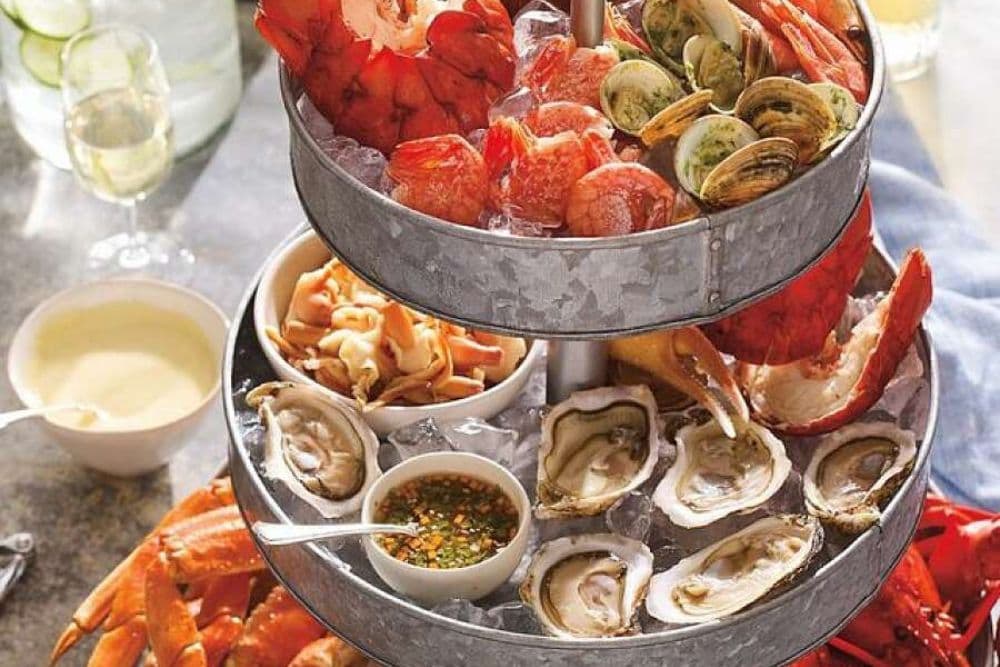 A silver two-tiered tray full of various kinds of freshly prepared seafood